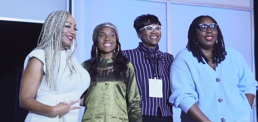 Four women panelists smiling together on stage