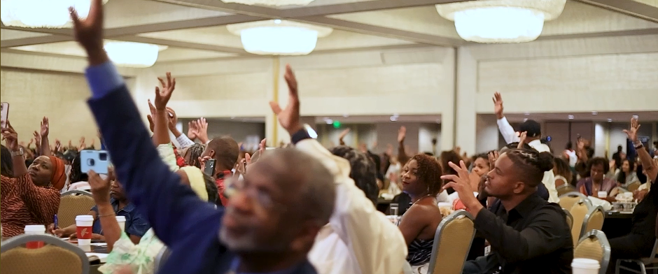 ABNC attendees raising their hands in a packed ballroom
